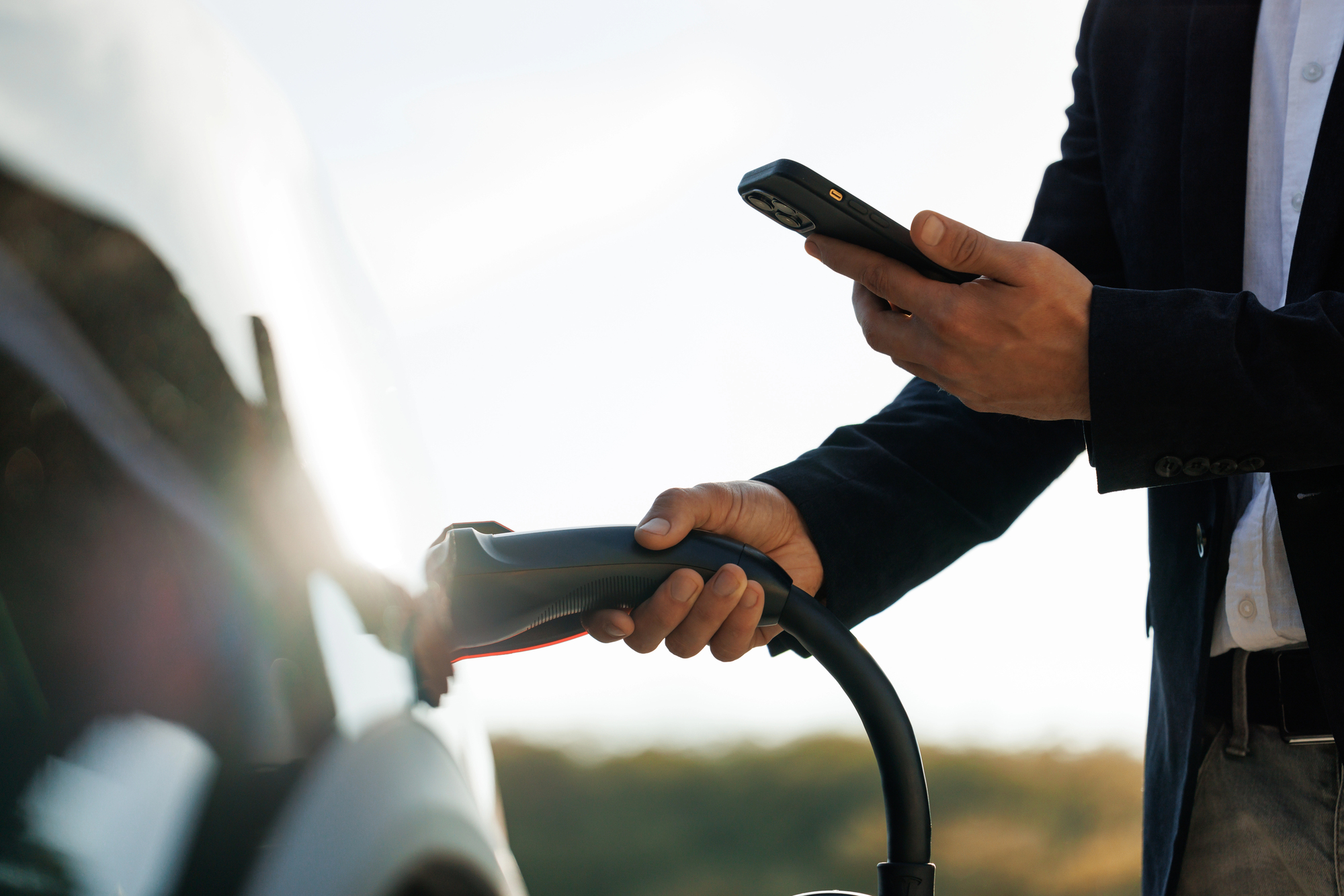 A business checking his phone while his EV vehicle is charging.