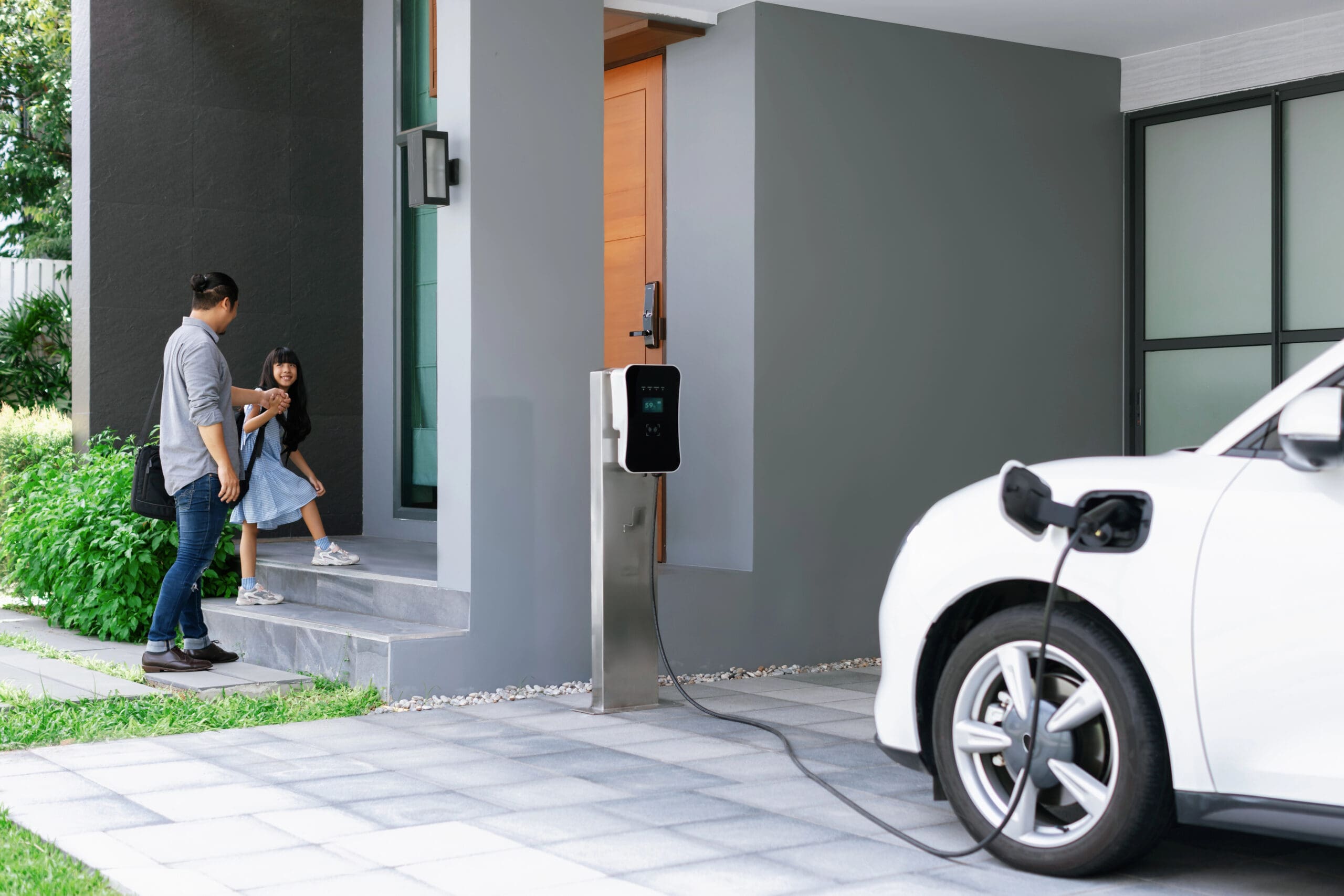 A father and his daughter going inside their home while their EV vehicle is charging